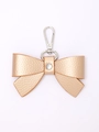Golden leather bow keychain with lychee texture and rhinestone center on white background - Gold