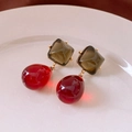 Dettaglio di orecchini in resina bordeaux e ambra su vassoio di ceramica bianca elegante - Orecchini-Oro-Verde-Rosso