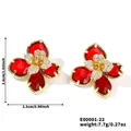 Primer plano de aretes de flores con pétalos rojos y centro de circonita cúbica - Piedra Roja Base Dorada