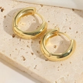 Minimalist thick golden huggie hoop earrings with a polished metallic finish on travertine - Hoop (Medium)