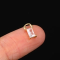Golden mini pendant with rectangular clear zircon stone held by fingers for scale - CC166 Rectangle / Gold