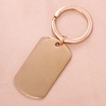 Dettaglio del portachiavi rettangolare in oro rosa lucido su elegante seta rosa - Oro rosa