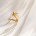 Dettaglio di un anello dorato ondulato in acciaio al titanio su elegante seta bianca - Linea d'onda a V placcata oro 18 carati