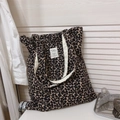 Detailed view of leopard print canvas tote bag with woven brand label and thick straps - Black and Grey Leopard
