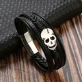 Detail of a multi-layer black braided leather bracelet with a silver skull and magnetic clasp - Black + Silver