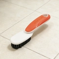 Detail of shoe brush with ergonomic orange handle and dense black cleaning bristles - Orange