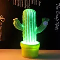 Luce notturna a LED a forma di cactus verde con base gialla su tavolo scuro - Piccolo Cactus Verde