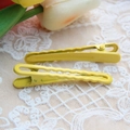 Pair of yellow metal hair clips with wavy texture on elegant beige lace fabric - Yellow