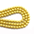 Close-up of polished golden glass pearl beads for DIY jewelry and necklace crafting - Yellow