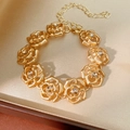 Dettaglio di un bracciale a fiori dorati con cristalli in una scatola di seta beige - Bracciale - Oro