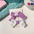 Two-piece children bow hair clips in solid purple and floral fabric on a display card - Purple Patchwork Bow Set