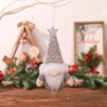 Grey knitted Christmas gnome ornament with silver star sequin hanging on a festive tree branch - Gray
