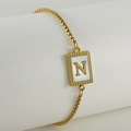 Pulsera minimalista de acero de titanio con letra N dorada en colgante de nácar blanco - Letra N