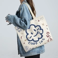 Grand sac cabas en toile blanc cassé avec graffitis porté par un mannequin en jean - Tournesol - Beige