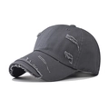 Close-up of distressed denim baseball cap with vintage frayed holes and washed texture - Gray