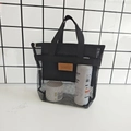Dettaglio della borsa a rete nera con etichetta in pelle marrone su tavolo bianco - Nero