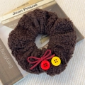 Detail of coffee lamb hair scrunchie with red bow and colorful buttons on vintage books - Dark Coffee