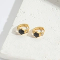 Golden star earrings with black enamel and zircons on textured stone background - Black