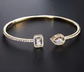Macro view of gold-plated open bangle with pear and emerald cut zircon stones - Gold (White Stone)