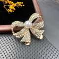 Broche nœud vintage avec base en métal doré, strass étincelants et détail de perle centrale - BZ081 Nœud Pavé
