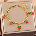 Bracelet chaîne Figaro dorée avec fraises en émail rouge et perles sur boîte à bijoux - Bracelet