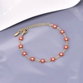Dettaglio del bracciale a catena dorata con fiori in smalto rosso e giallo e chiusura a moschettone - Rosso-Oro