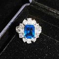 Makroaufnahme eines Ringes mit blauem Edelstein im Smaragdschliff und Kristallhalo - Blauer Zirkon Ring (Einstellbar)