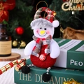 Close-up of a plush Christmas snowman ornament sitting on books with festive background - Bead Chain Snowman