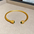 Detail eines 24k goldfarbenen Armreifs mit grünen Edelsteinen und Zirkon-Akzenten - Vergoldeter Kürbis-Stil