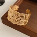 Dettaglio di un ampio bracciale a polsino dorato con intricati motivi traforati in pizzo - Bracciale Rigido Aperto Largo Cavo / Oro