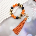 Dettaglio di perline in silicone arancione e leopardate con nappa in pelle e gancio oro - Arancione