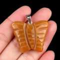 30x35mm natural orange agate butterfly pendant with silver bail shown in hand - Topaz