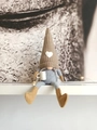 Detailopname van een kerstkabouter met bruine gebreide muts en hart op een witte plank - Khaki Vrouw