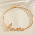 Detailaufnahme einer goldfarbenen Kette mit Amore-Schriftzug für Taille oder als Halskette - Schreibschrift Amore Buchstaben Stil / Gold