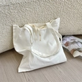 Detail of white canvas tote bag with drawstring texture on a cream boucle sofa - Two White Ribbons