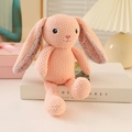 Pink knitted bunny plush toy with floral inner ears in a cozy warm home setting - 25cm Pink Rabbit