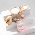 Gouden sleutelhanger met oceaanthema voorzien van acryl schelpen en een zeester - Roze