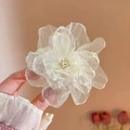 Close-up of a white transparent organza flower hair clip held against a pink background - Cream White Camellia