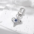 Zilveren hart sleutelhanger met blauw boze oog op een witte getextureerde steen - Zilver Puntig Hart Koningsblauw Boze Oog