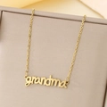 Dettaglio macro di una collana dorata con ciondolo grandma in una confezione regalo di lusso - Stile Lettera grandma(KN281814-LX)