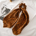 Detailed shot of leopard print satin hair scrunchie with long ribbon on white fabric - Brown Dotted Leopard