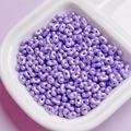 Macro detail of purple pearlescent peanut beads for DIY jewelry making in a white bowl - Purple