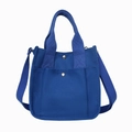 Blue canvas tote bag with adjustable shoulder strap and snap front pocket in studio shot - Blue