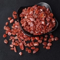 Polished red agate crystal shards spilling from a black bowl on textured background - Southern Red Agate / 7-9mm 100g