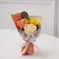 Detailed close-up of mini soap rose bouquet with orange and yellow petals and love ribbon - Orange