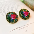 Close-up of vintage round gold earrings with colorful rhinestones on a book page - Multi-color Style (HE12671)