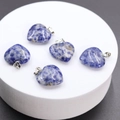 Natural blue lapis lazuli heart pendants with metal rings on a white display stand - Sodalite