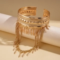 Dettaglio di un bracciale da braccio boho dorato con catene a nappa e ciondoli a piuma - Oro