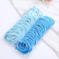 Close-up of blue seamless towel hair ties set in transparent packaging on white fabric - Blue