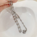 Collana a catena con cuori argentati e perla d'acqua dolce su un piatto di ceramica bianca - Catena a cuore in acciaio al titanio argento